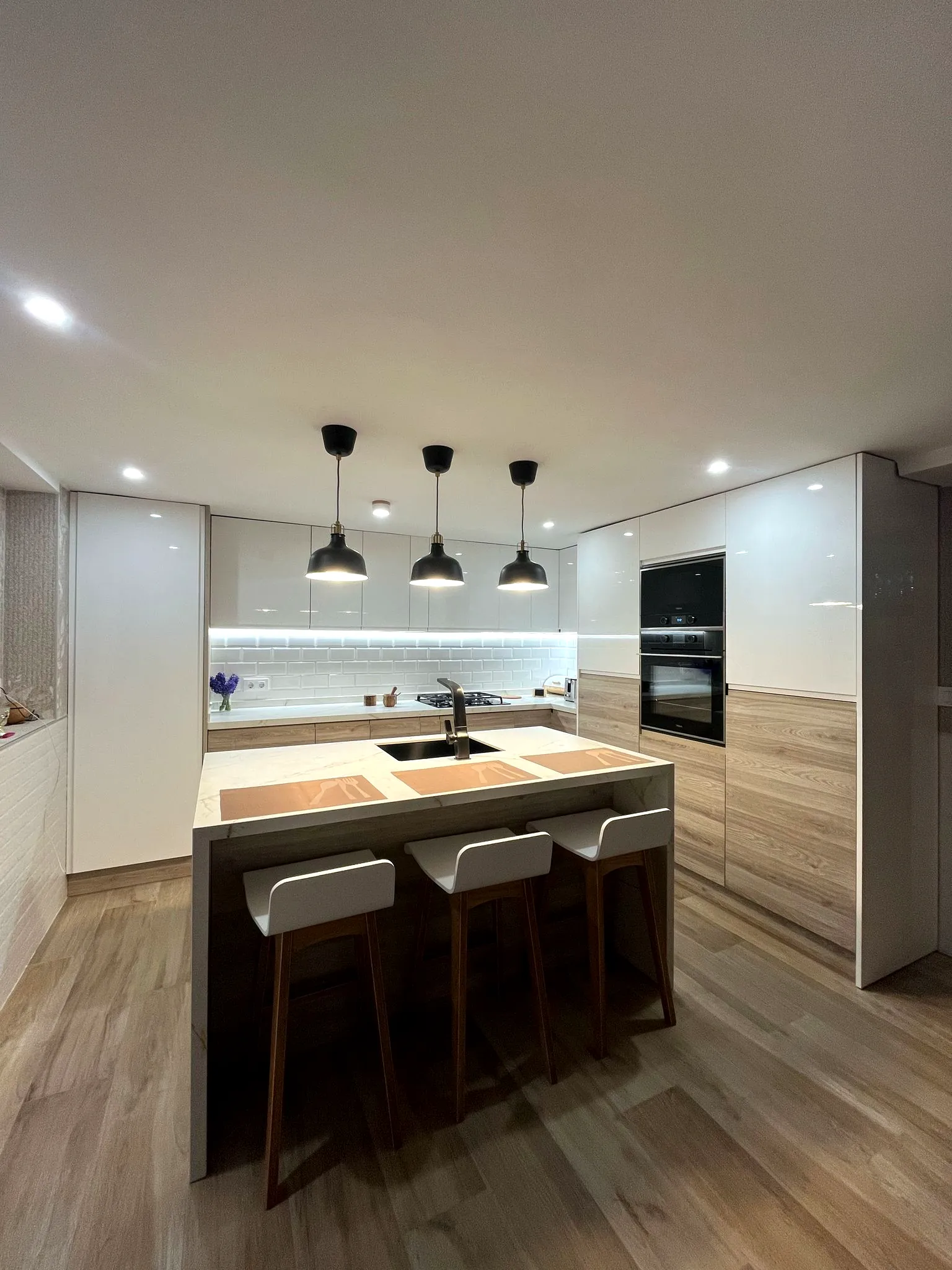 Instalación de cocina con isla y muebles en madera y blanco